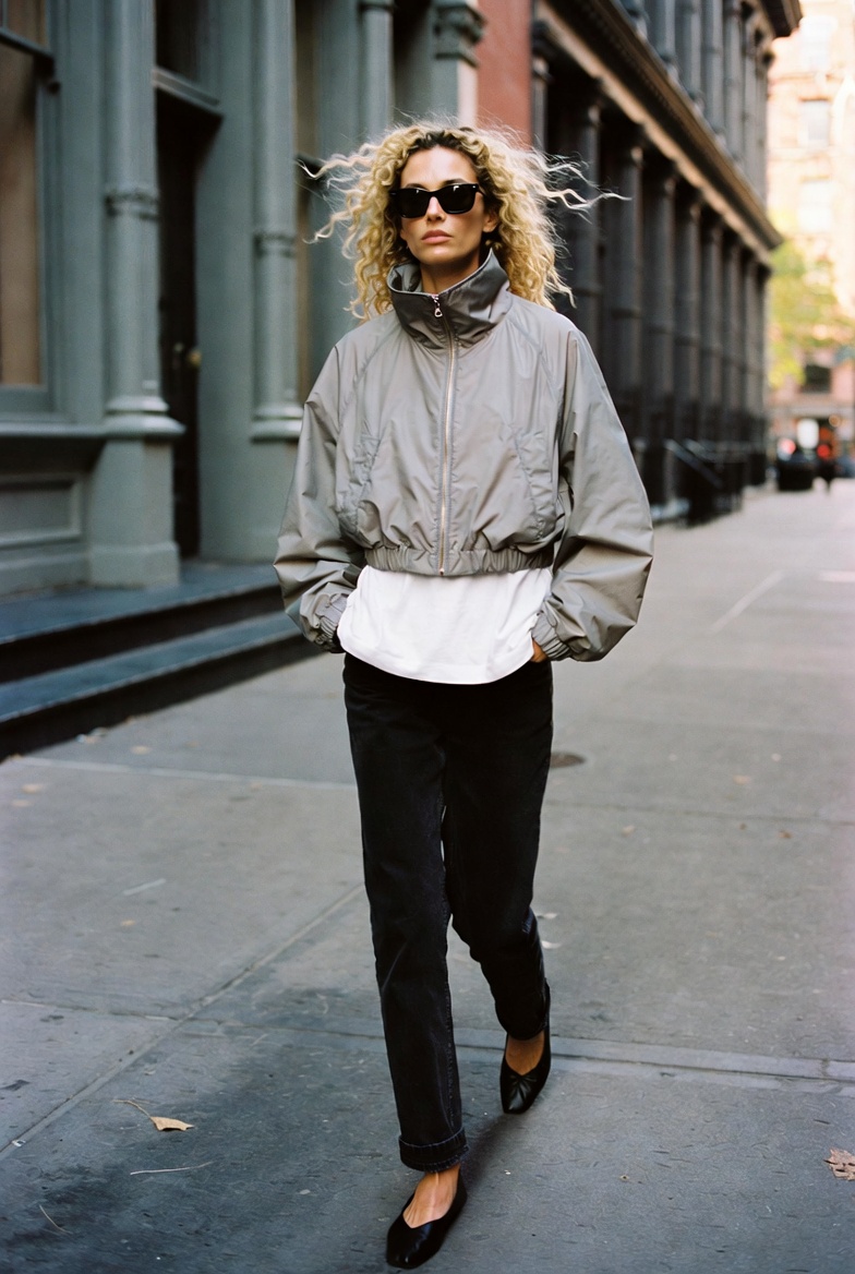 Technical Ease — a tall slender model on a New York street in early autumn light wearing a cropped silver-grey technical windbreaker over a white t-shirt, the ESVRA Fashion edit on the Fall 2026 technical jacket trend